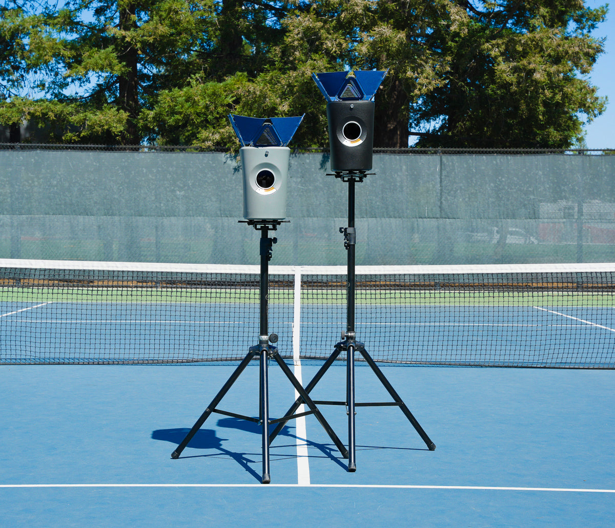 Two Hydrogen Sports ball machines mounted on elevated stands on a tennis court.